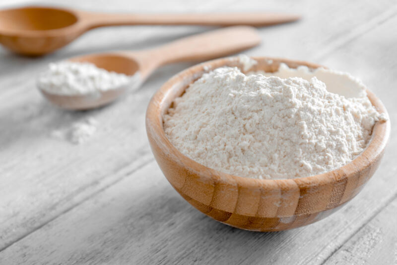 A wooden bowl of plain white flour on a table 