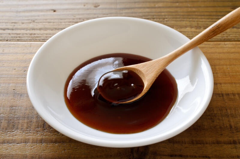 A small bowl of Worcestershire sauce with a wooden spoon in it