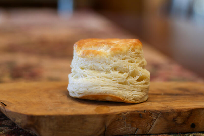 Selective focus close-up of one homemade buttermilk biscuit on a wooden board
