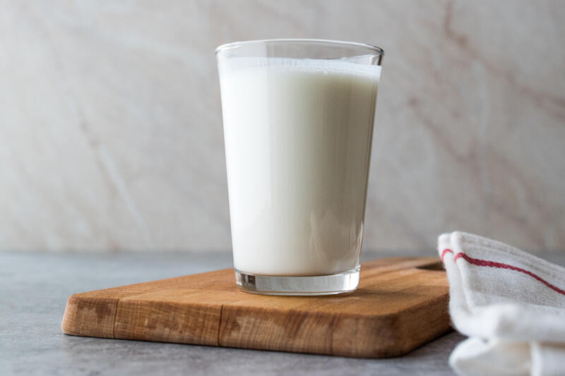 A glass of buttermilk on a cutting board on a kitchen counter