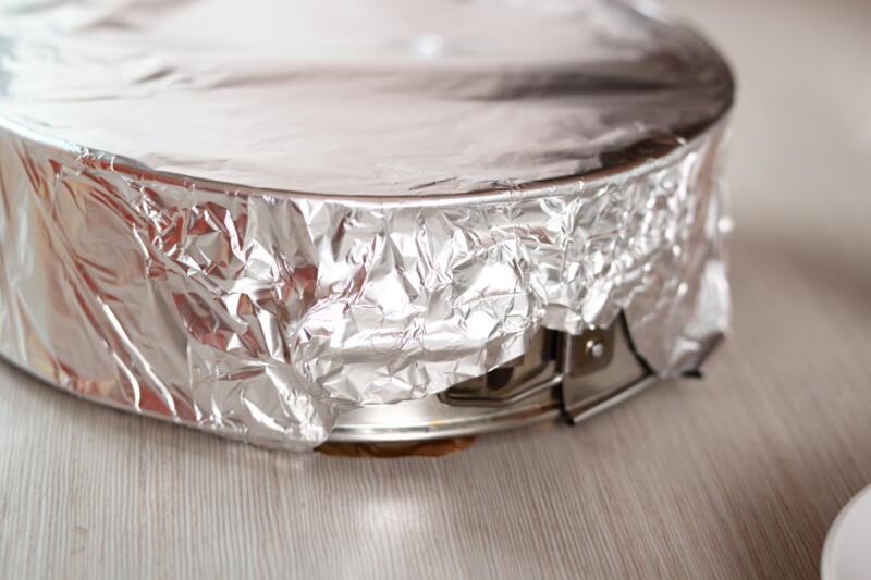 A cake in a mold wrapped with aluminum foil for storage