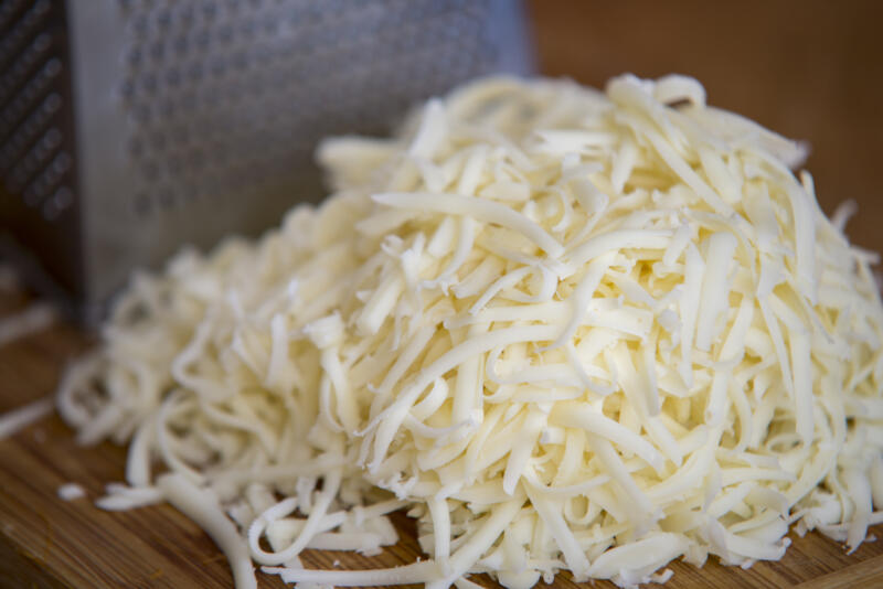 Shredded Mozzarella cheese on a cutting board