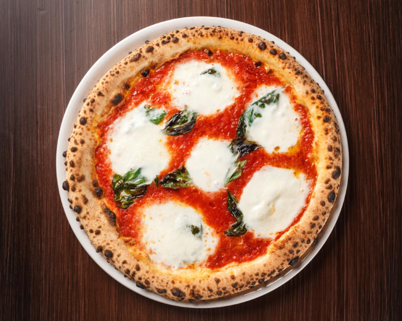 Pizza Margherita with Mozzarella di Bufala on a plate and on a table
