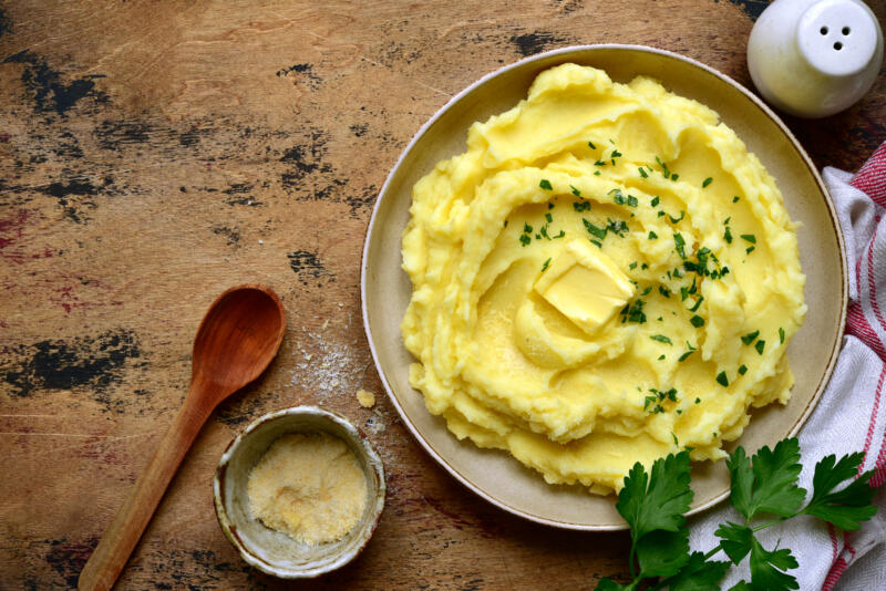 A plate of mashed potatoes with butter topped with greens