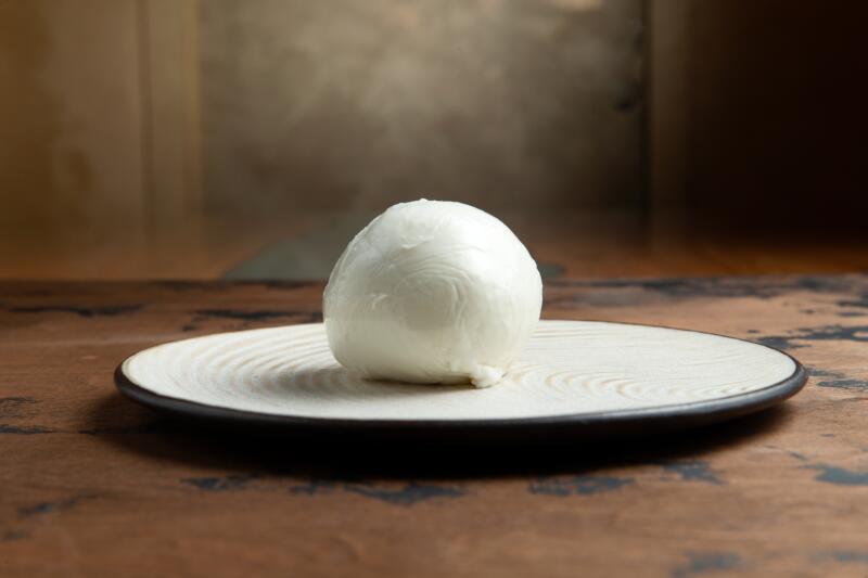 A ball of Mozzarella cheese on a round plate on table