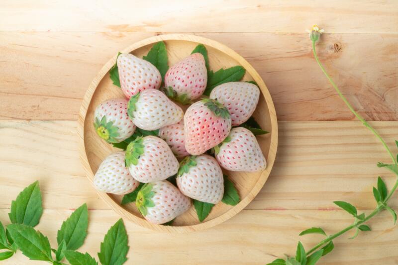 Japanese pink snow strawberries variety in a wooden plate on a table