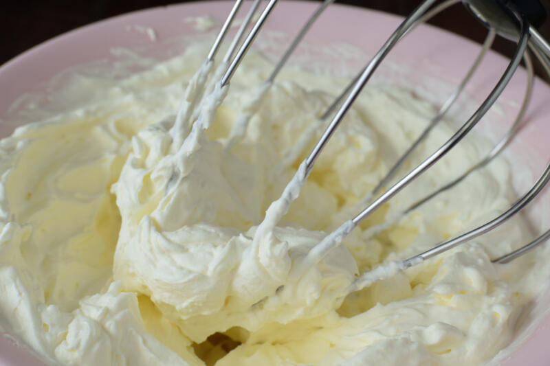 Whipping icing sugar and whipped cream in a pink bowl