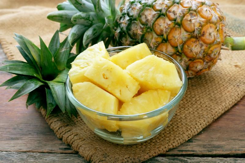 Pineapple slices and pineapple on the wooden background