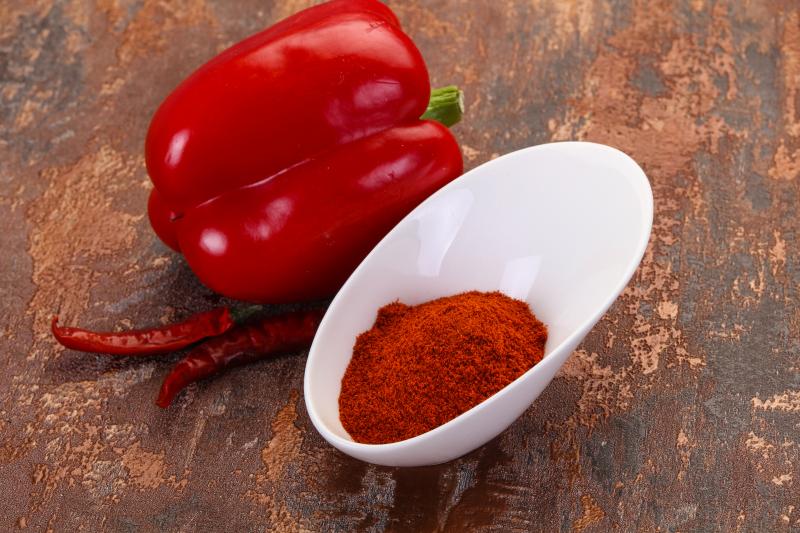 Sweet paprika in a bowl as well as fresh peppers 